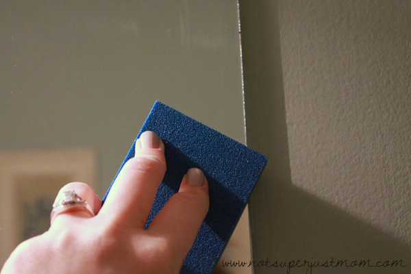 The outer edge of the mirror lightly roughed up with a sanding block, the dulled band just visible along the top edge of the glass