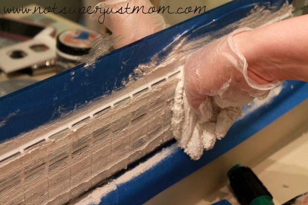 Excess grout being scraped back off the surface of the tiles, leaving the grout lines filled